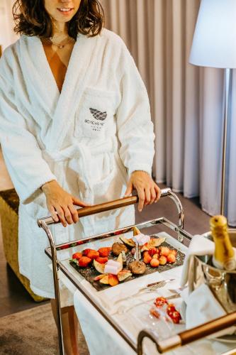 a woman in a bathrobe standing next to a tray of food at Boticas Hotel Art & SPA in Boticas