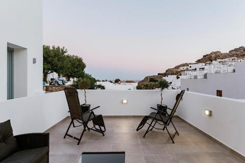 a balcony with two chairs and a couch at Lindos Calmare Suites in Líndos