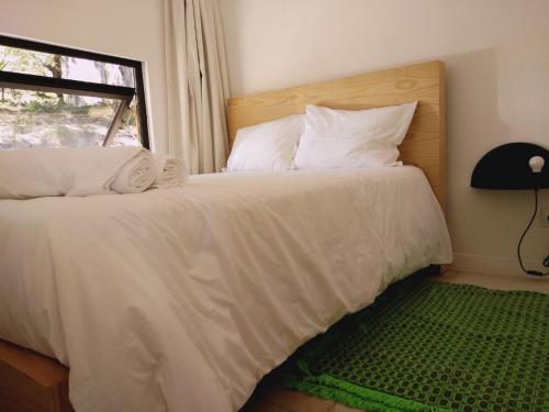 una camera da letto con un letto con lenzuola bianche e una finestra di Ninho da Avó Selvagem a Montalegre