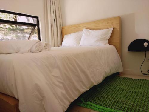 a bedroom with a bed with white sheets and a window at Ninho da Avó Selvagem in Montalegre