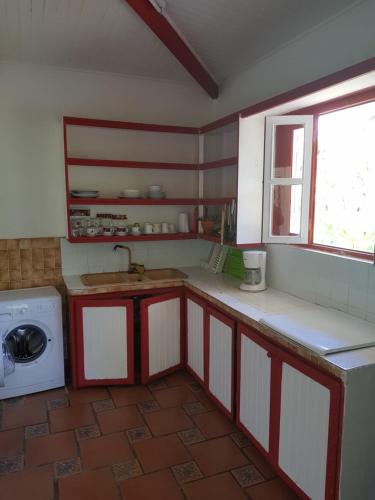 a kitchen with red and white cabinets and a window at Hotel La Chaumiere in Matoury