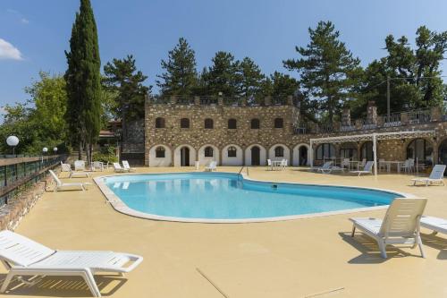 a swimming pool with chairs and a building at Villa Serra Alta in Fermignano