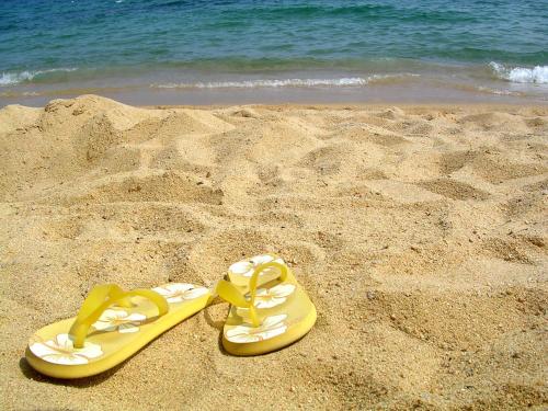 a pair of yellow flip flops in the sand on the beach at BE BIO Hotel be active - Nähe historischer Hafen in Tönning