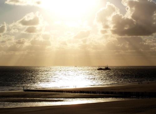 a boat in the ocean with the sun in the sky at BE BIO Hotel be active - Nähe historischer Hafen in Tönning