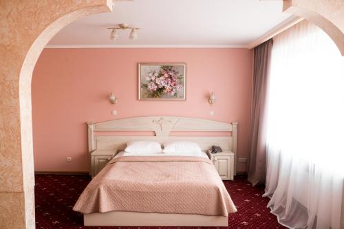 a bedroom with a bed and a painting on the wall at Hotel Halychyna in Ternopilʼ