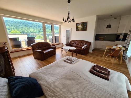 a living room with a bed and chairs and a large window at Penthouse apartmán rezidencia Minerál in Bardejovské Kúpele