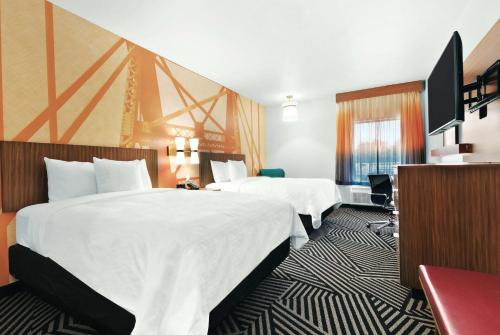 a hotel room with two beds and a flat screen tv at La Quinta by Wyndham Waco Baylor Downtown in Waco