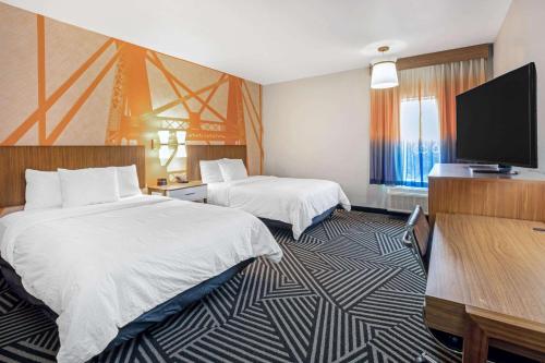 a hotel room with two beds and a flat screen tv at La Quinta by Wyndham Waco Baylor Downtown in Waco