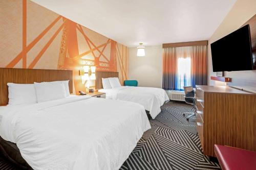 a hotel room with two beds and a flat screen tv at La Quinta by Wyndham Waco Baylor Downtown in Waco