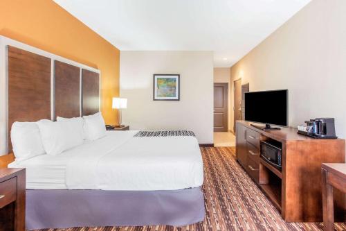 a hotel room with a bed and a flat screen tv at La Quinta by Wyndham Gonzales TX in Gonzales