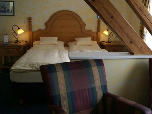 a bedroom with two twin beds and a chair at Hotel Rauch in Attendorn