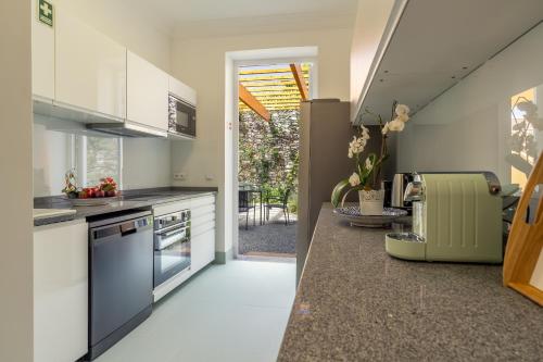 a kitchen with white cabinets and a stove top oven at Casa da Cal - by Casas na Ilha in Câmara de Lobos