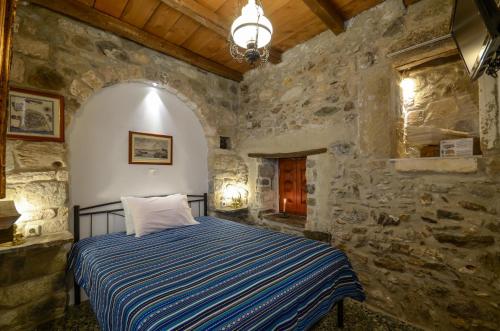 a bedroom with a bed in a stone wall at Venetiko Apartments in Naxos Chora