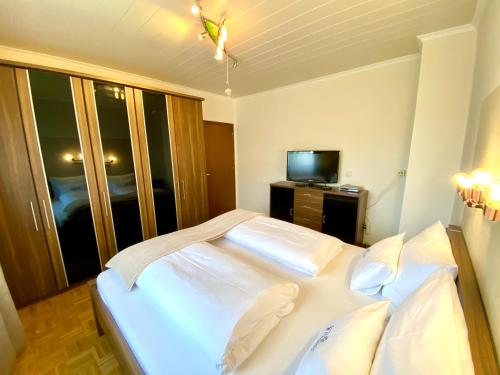 a bedroom with a white bed and a television at Pleschinhof in Velden am Wörthersee
