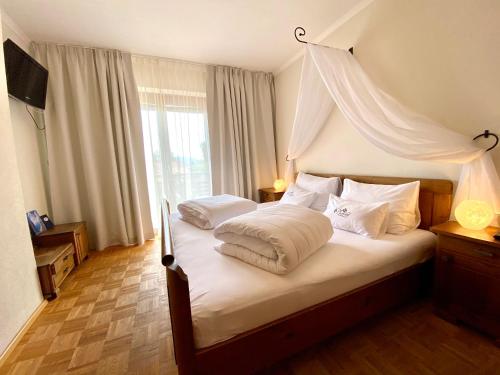 a bedroom with a canopy bed with white pillows at Pleschinhof in Velden am Wörthersee