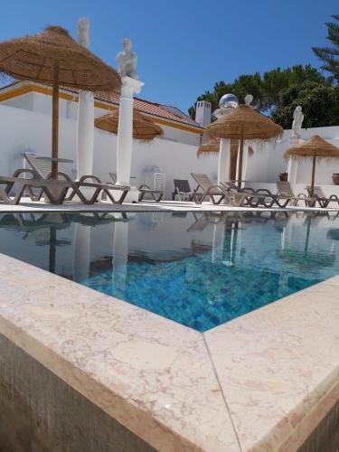 a swimming pool with chairs and umbrellas at HOTEL S - ALOJAMENTO LOCAL in Castro Verde