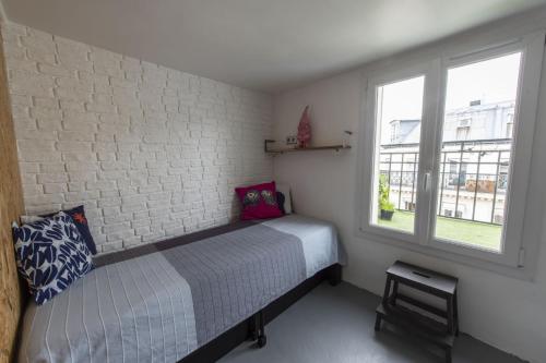 um quarto com uma cama e uma parede de tijolos em Piaf em Paris