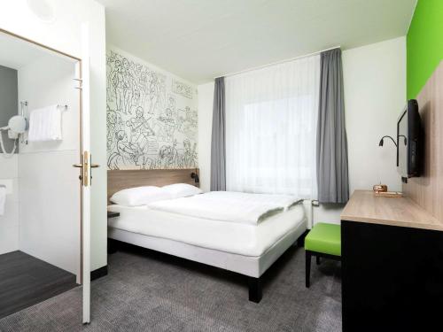 a bedroom with a white bed and a green chair at ibis Styles Halle in Halle an der Saale