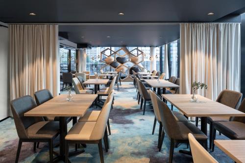 a restaurant with wooden tables and chairs and windows at Original Sokos Hotel Kupittaa in Turku