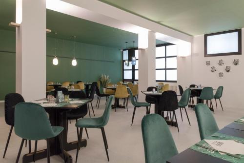 a dining room with tables and green chairs at ALBERGO 900Strati in Bergamo