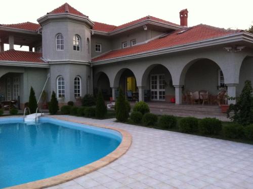 duży dom z basenem przed nim w obiekcie Sunny House w mieście Skopje
