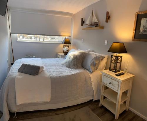 Un dormitorio con una gran cama blanca y una mesa en Swamp Fox luxury 2BR Dutch Barge en Goolwa