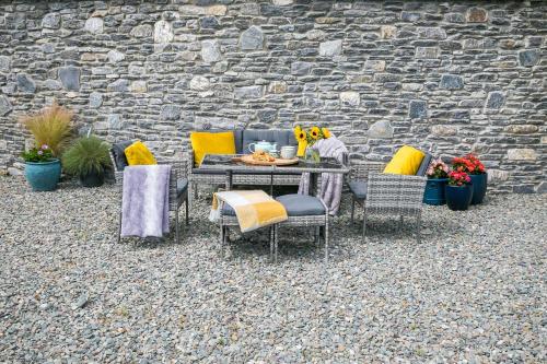 a table and chairs and a stone wall at The Beeches in Killarney