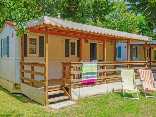 a small house with a porch and two chairs at Portofelice Camping Village in Eraclea Mare