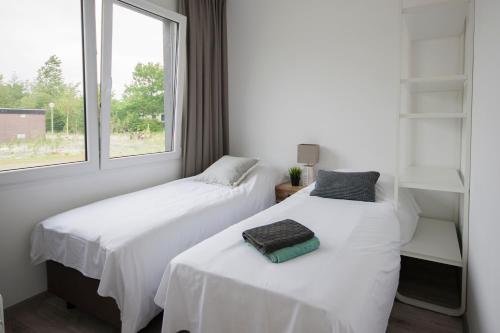 Dos camas en una habitación con ventana. en RCN Vakantiepark Bungalow de Dukdalf, en Kamperland