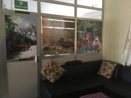 a living room with two large windows and a couch at Dodoma Siesta Inn in Dodoma