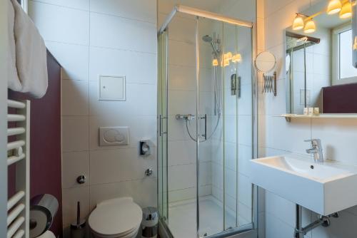 a bathroom with a shower and a toilet and a sink at Arthotel ANA Style Augsburg in Augsburg
