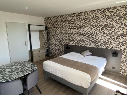 a bedroom with a bed and a table and a wall at Studios Pellisson in Cognac