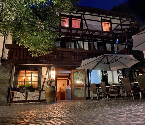 a building with tables and umbrellas in front of it at Hotel-Restaurant Zur Traube in Altenahr