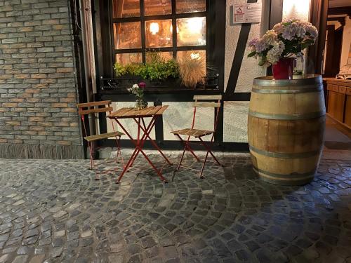 a table and two chairs and a barrel with flowers at Hotel-Restaurant Zur Traube in Altenahr