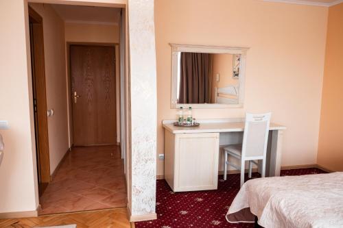 a bedroom with a desk and a bed and a mirror at Hotel Halychyna in Ternopilʼ