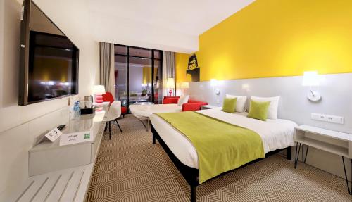 a hotel room with a bed with a yellow wall at Ibis Styles Wroclaw Centrum in Wrocław