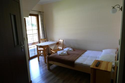 a bedroom with a bed and a table and a window at Dwór Bogdałów in Koniaków