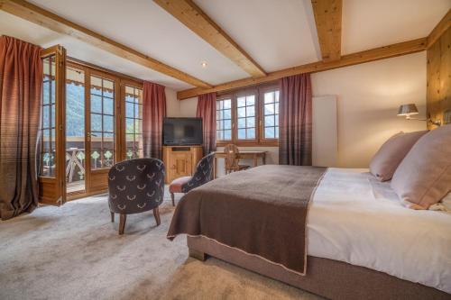 - une chambre avec un grand lit et une télévision dans l'établissement Auberge du Bois Prin, à Chamonix-Mont-Blanc