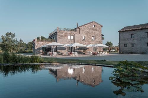 a building with tables and umbrellas next to a lake at i Cacciagalli Wine Resort in Teano