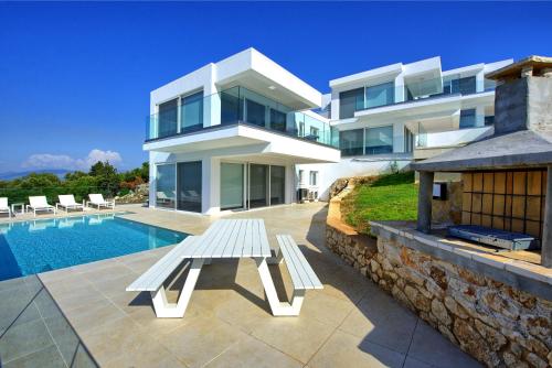 a house with a white bench next to a swimming pool at Villa Nafsika by PosarelliVillas in Perítheia