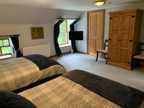 a bedroom with two beds and a television in it at Lodge at Lochside in Bridgend of Lintrathen