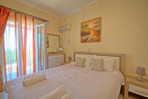 a bedroom with a large white bed and a window at Villa Giador by PosarelliVillas in Perítheia