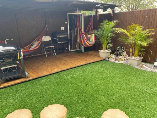 a backyard with green grass and hammocks and a fence at Quiet, spacious double bedroom! in Peterborough