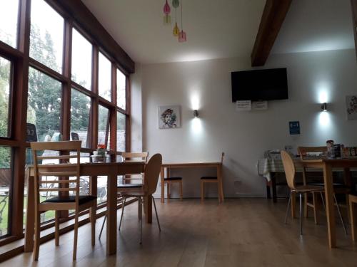 a dining room with a table and chairs and windows at Brook Barn B&B in Hale