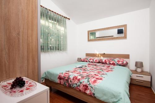 a bedroom with a bed with a floral bedspread at Apartman Tanja in Fažana