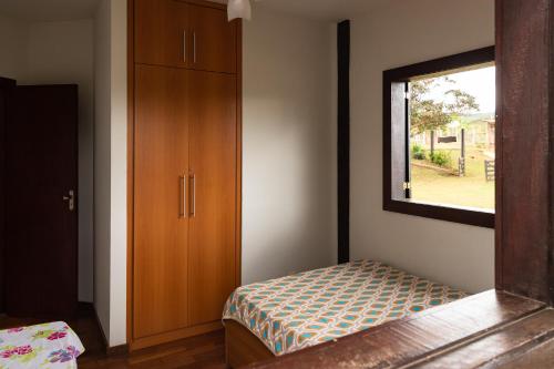 a bedroom with a bed and a dresser and a window at Estâncias da Serra dos Alves in Itabira