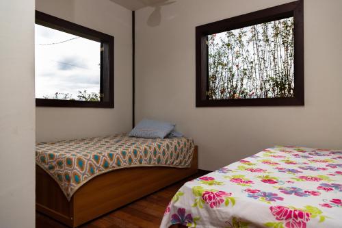 a bedroom with a bed and two windows at Estâncias da Serra dos Alves in Itabira