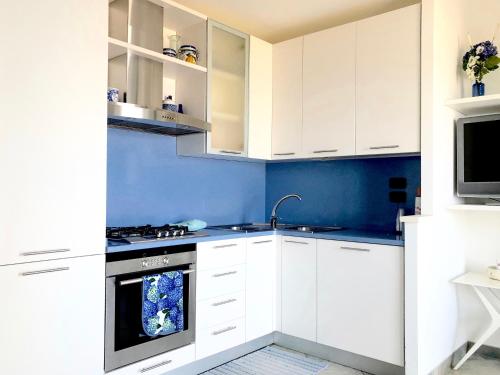 een witte keuken met blauwe muren en witte kasten bij Casa Confalonieri fronte mare con vista mozzafiato in San Benedetto del Tronto