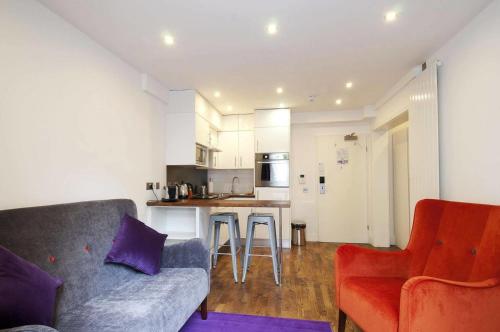 Camden Prime ApartHotel في لندن: غرفة معيشة مع أريكة ومطبخ