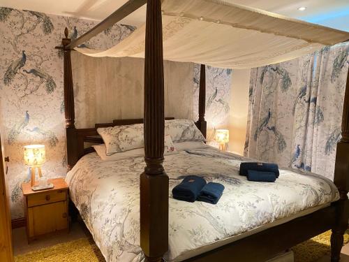 a bedroom with a canopy bed with blue towels on it at Lake District romantic get away in 1 acre gardens off M6 in Penrith